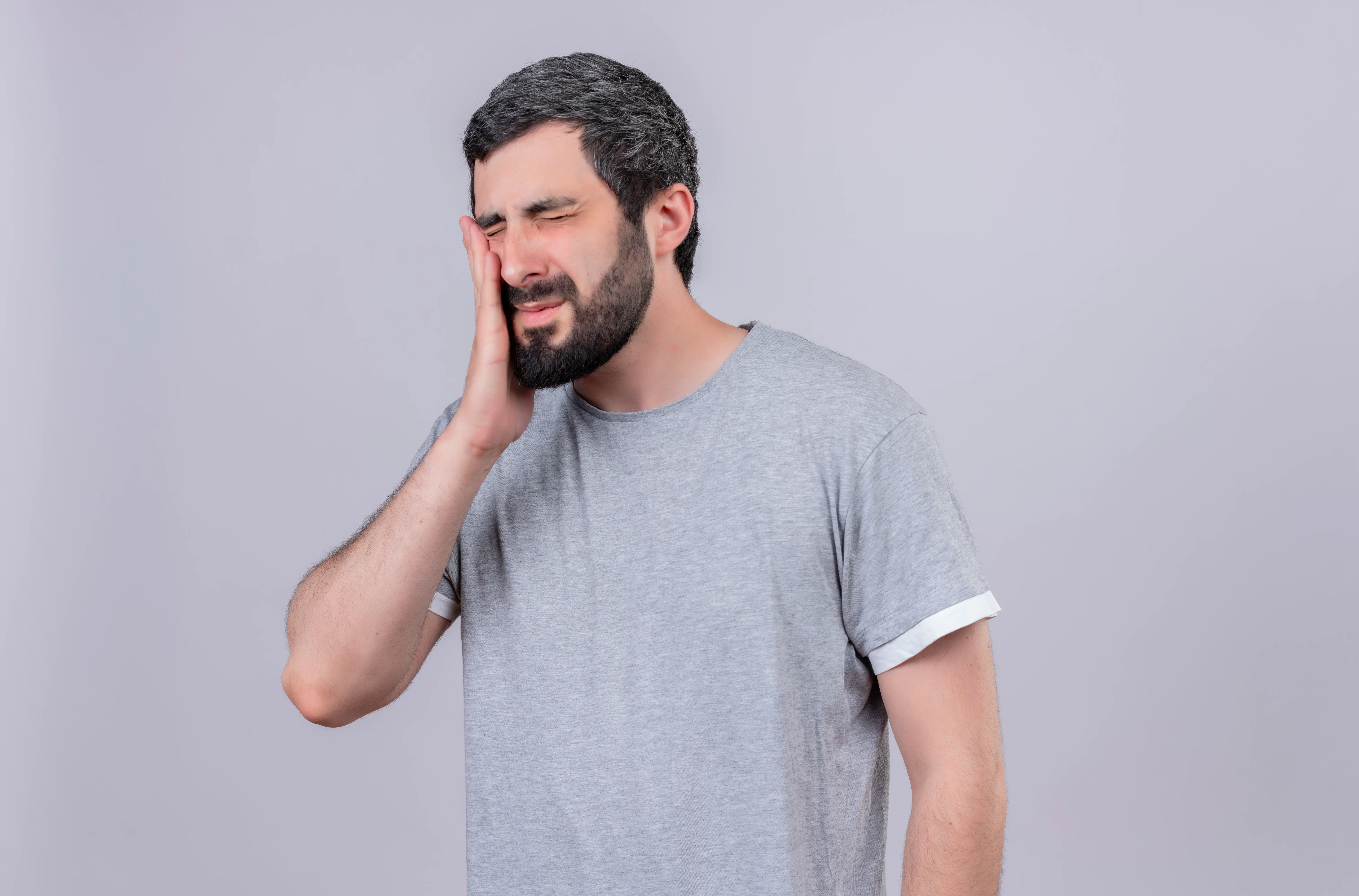 Man feeling intermittent tooth pain touching cheek without cavity