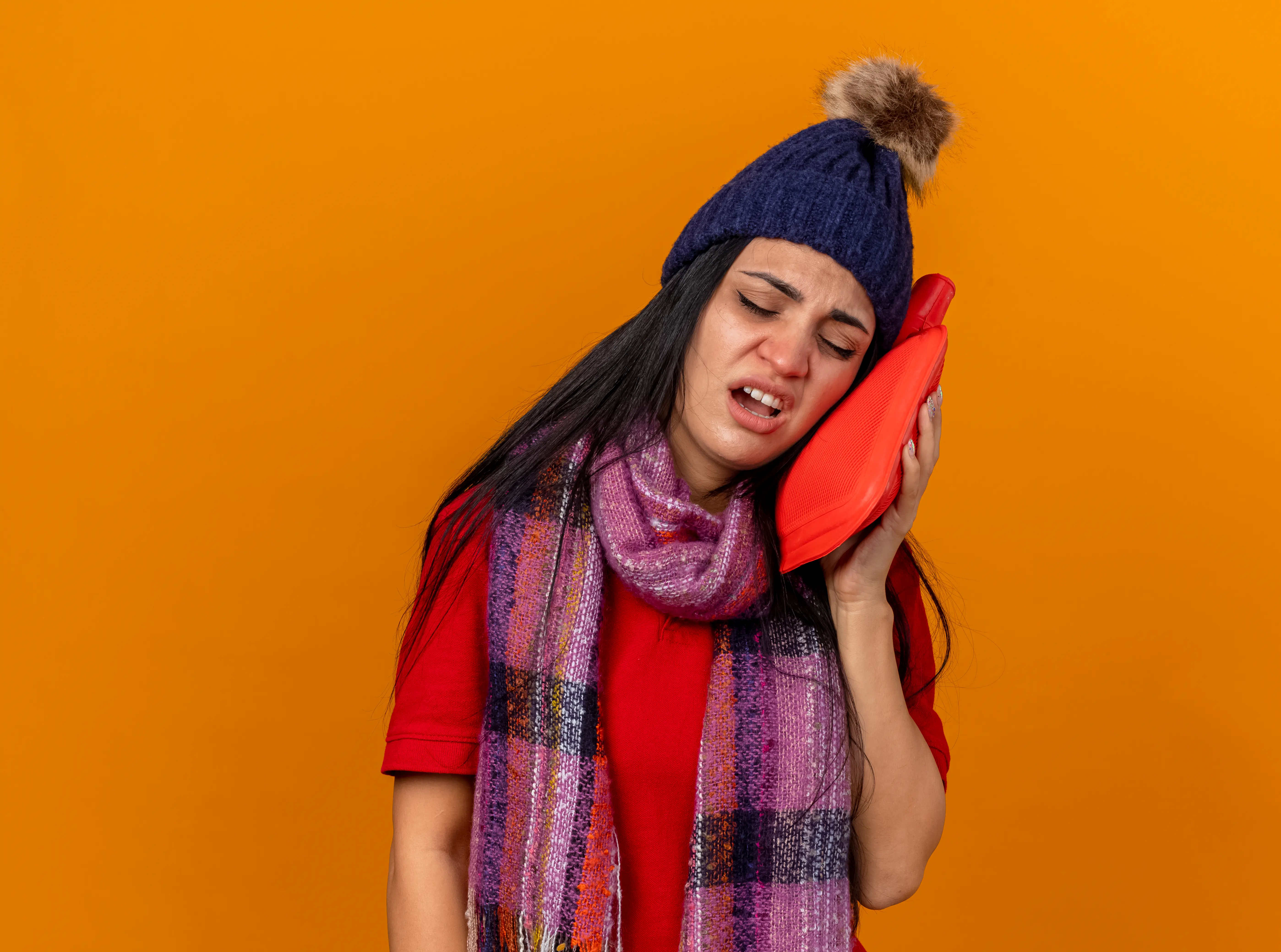 Woman feeling tooth pain from cold air sensitivity wearing winter clothes